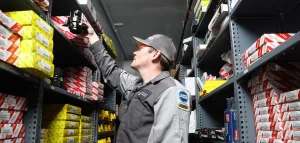 Inside Lexology Auto Shop, a man inspects a shelf filled with auto parts in a spacious warehouse, photo by Dogs of Design